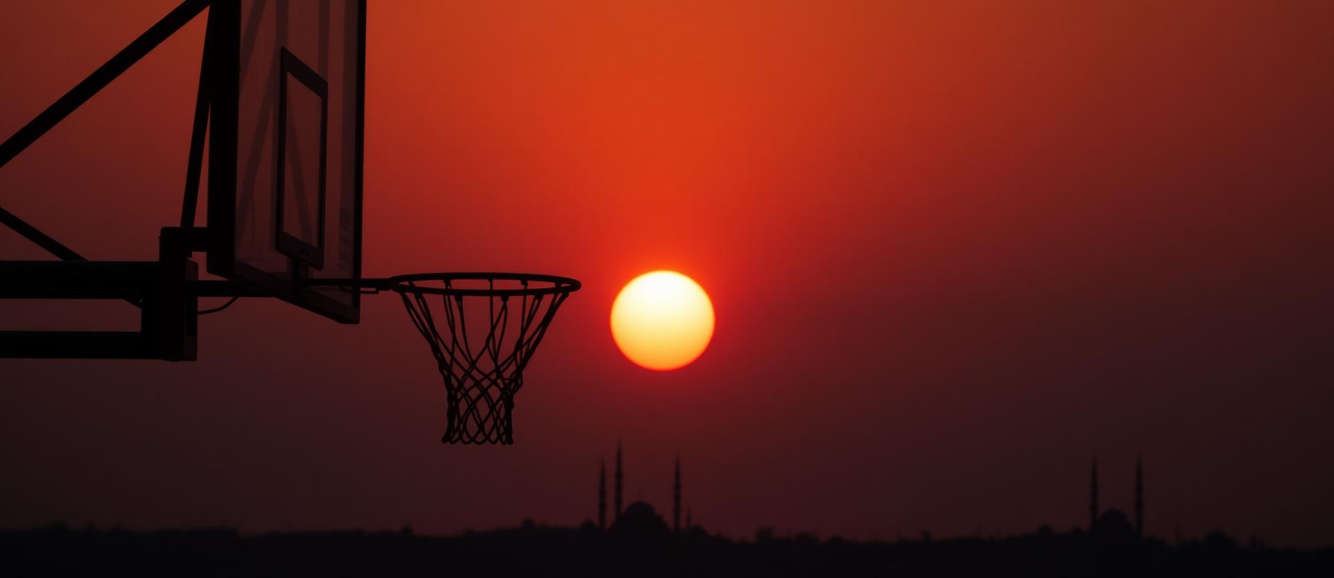 Maghrib light pouring over a basketball hoop with city minarets on the horizon